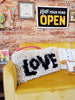 cozy long throw pillow with shaggy tassels and love in black text 