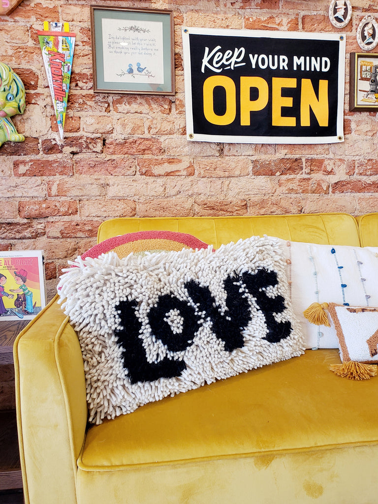 cozy long throw pillow with shaggy tassels and love in black text 