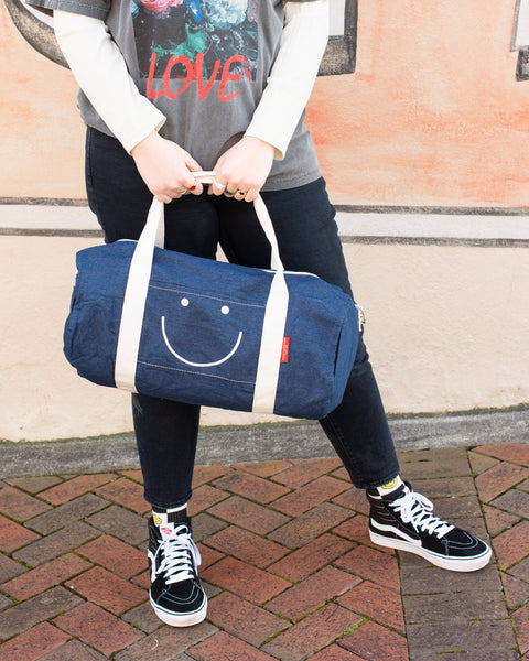 Denim duffle bag with cloth straps and white smiley design